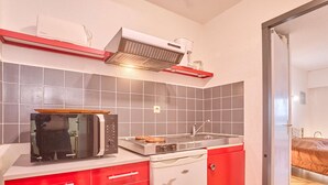 Une cuisine de taille réduite équipée d’un four à micro-ondes, d’une cuisinière et d’un évier.