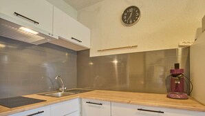 A modern kitchen with white cabinets, a stainless steel sink, a wooden countertop, and a coffee maker. - Charming T1 bis with private garden in Barbotan-les-Thermes (Barbotan-les-Thermes)