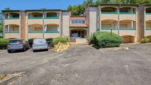 A multi-story hotel with a central entrance, parking lot, and a small garden area. - Charming T1 bis with private garden in Barbotan-les-Thermes (Barbotan-les-Thermes)