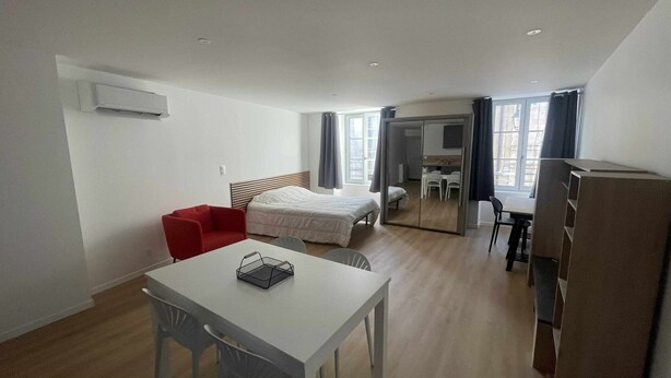 A modern hotel room with a bed, a desk, a chair, and a small dining area. - Centrally located air-conditioned studio with wifi and fully equipped kitchen (Châteauroux)