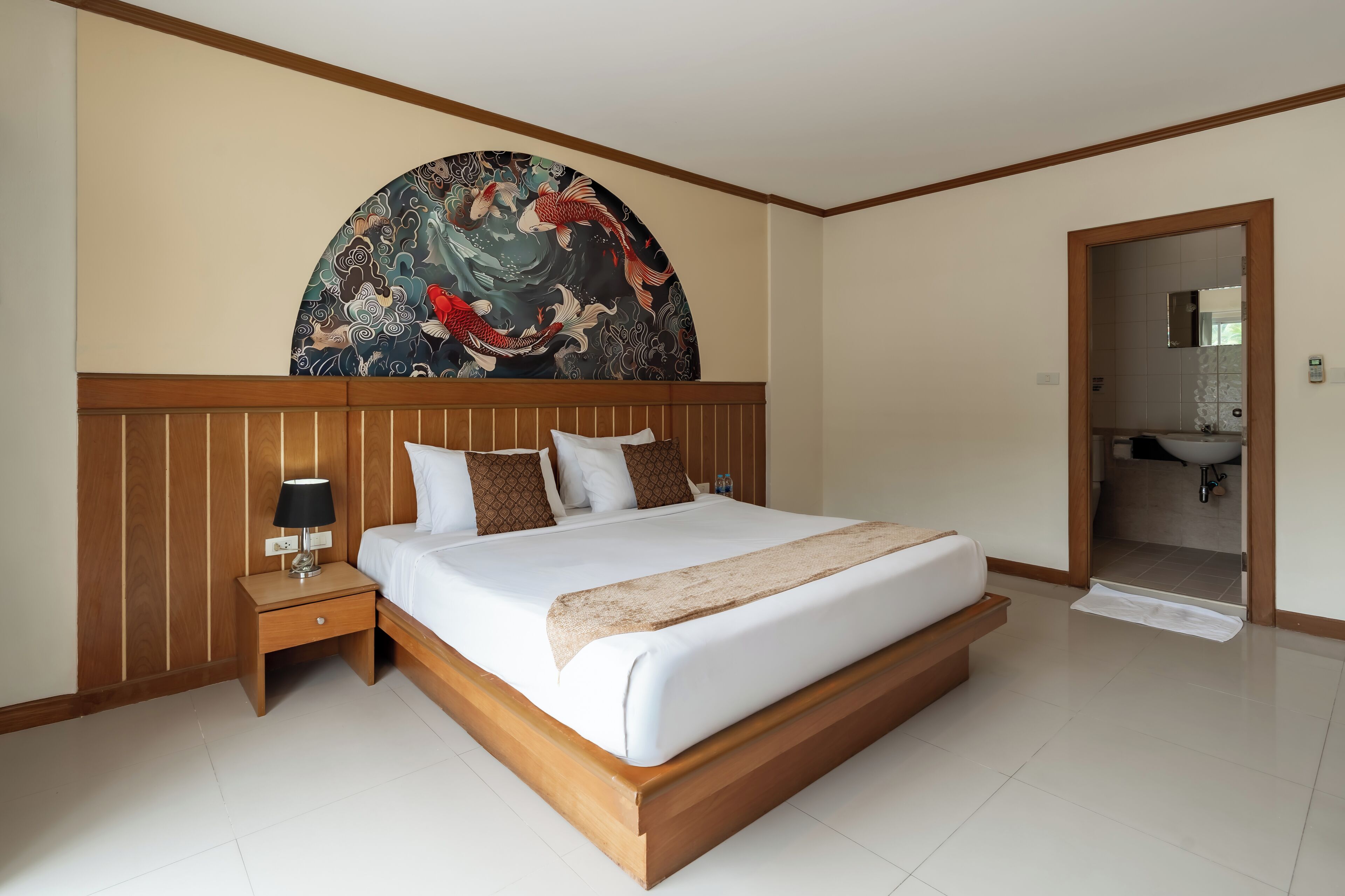 Una habitación de hotel con una cama grande, cabecera de madera, una mesita de noche con lámpara y un mural en la pared.