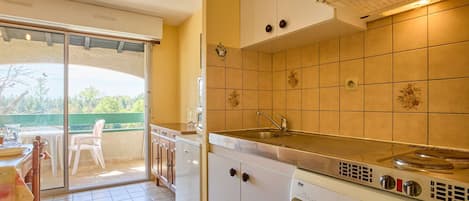 Una cocina compacta con lavadora incorporada, un lavabo y una pequeña zona de comedor con mesa y sillas.