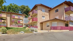 Un hotel de varios pisos con balcones, un cartel que dice "Le BeauLieu" y un área de estacionamiento al frente.