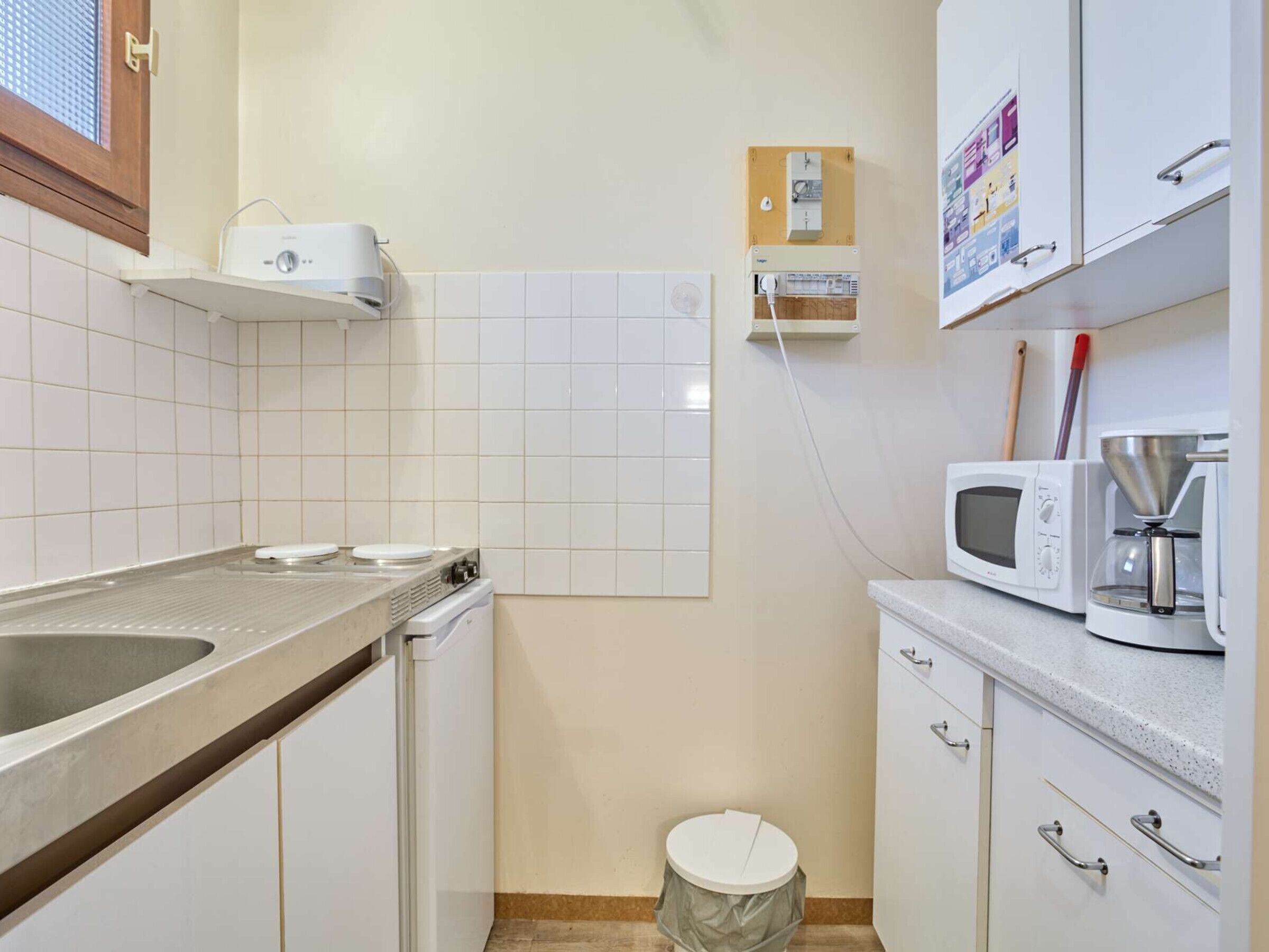 Een kleine keuken met een spoelbak, magnetron en koffiezetapparaat.