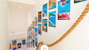 Un escalier muni d’une barrière en corde, dont les murs sont décorés de diverses affiches de voyage.
