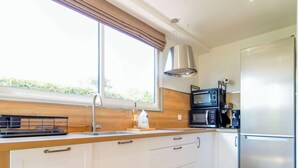 Une cuisine moderne avec des meubles blancs, un réfrigérateur en acier inoxydable, un four à micro-ondes double et un plan de travail en bois.