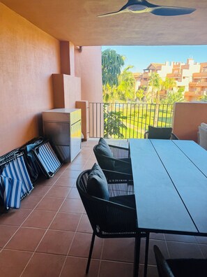 Un balcon avec une table et des chaises, un petit canapé et un porte-bagages.