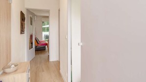 A hallway with a wooden floor, a white door, and a bed with a colorful blanket. - Renovated apartment in Hendaye with air conditioning and parking (Hendaye)