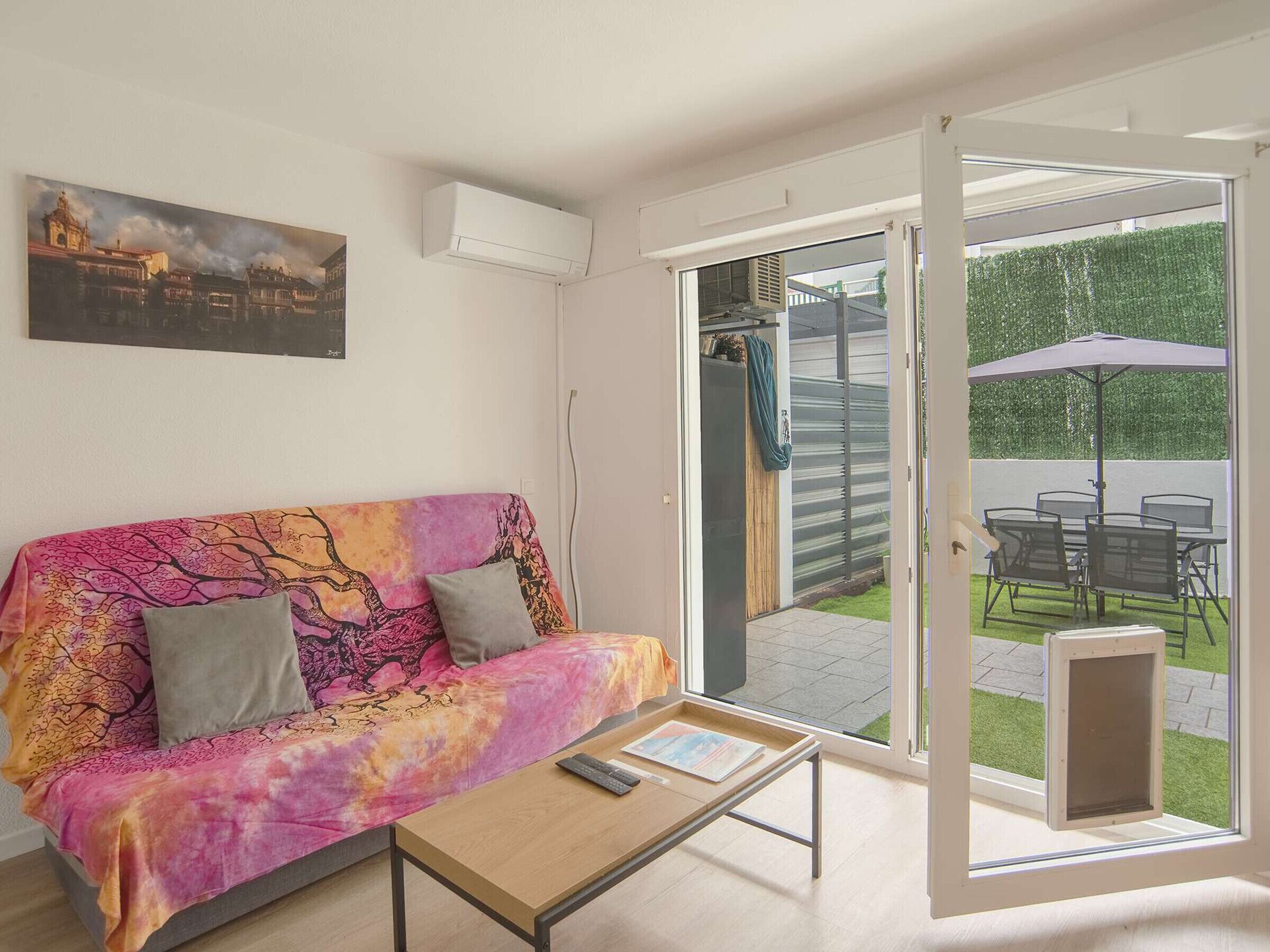 A room with a sofa, a coffee table, and a sliding glass door leading to an outdoor patio with a table and chairs.