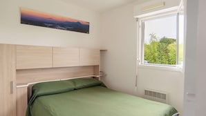 A bedroom with a bed, a headboard, a window, and a painting on the wall. - Renovated apartment in Hendaye with air conditioning and parking (Hendaye)