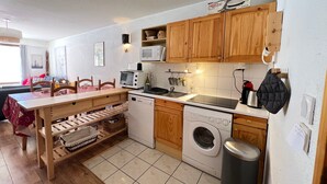 Une cuisine compacte dotée de meubles en bois, d’un four à micro-ondes, d’un lave-vaisselle et d’une machine à laver.