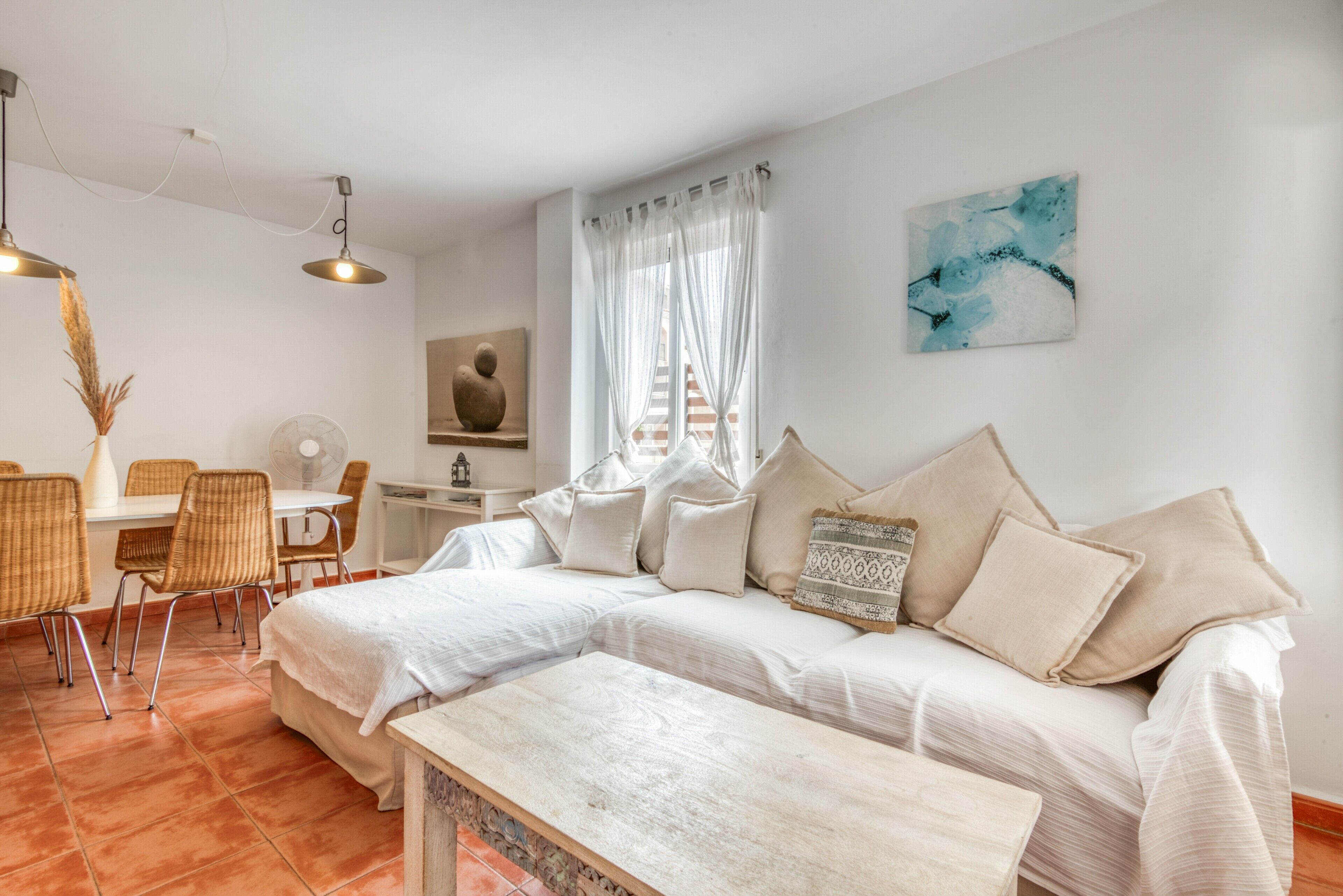 Une chambre moderne comprenant un lit, une table à manger avec des chaises, une petite table et une fenêtre avec des rideaux.