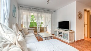 Una camera da letto con un ampio letto, una televisione e un balcone con tende.
