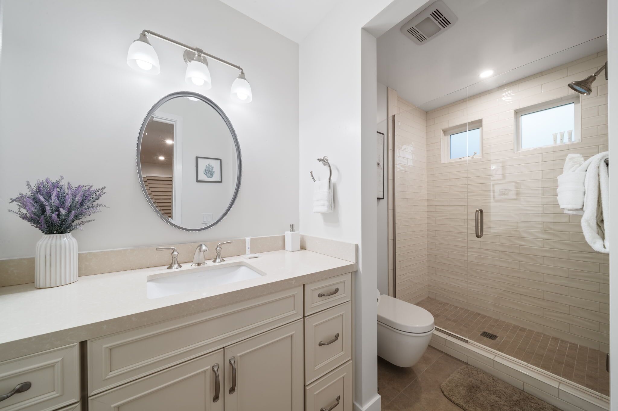 Une salle de bain moderne dotée d’un grand miroir, d’un meuble-lavabo, d’un lavabo et d’un espace douche.
