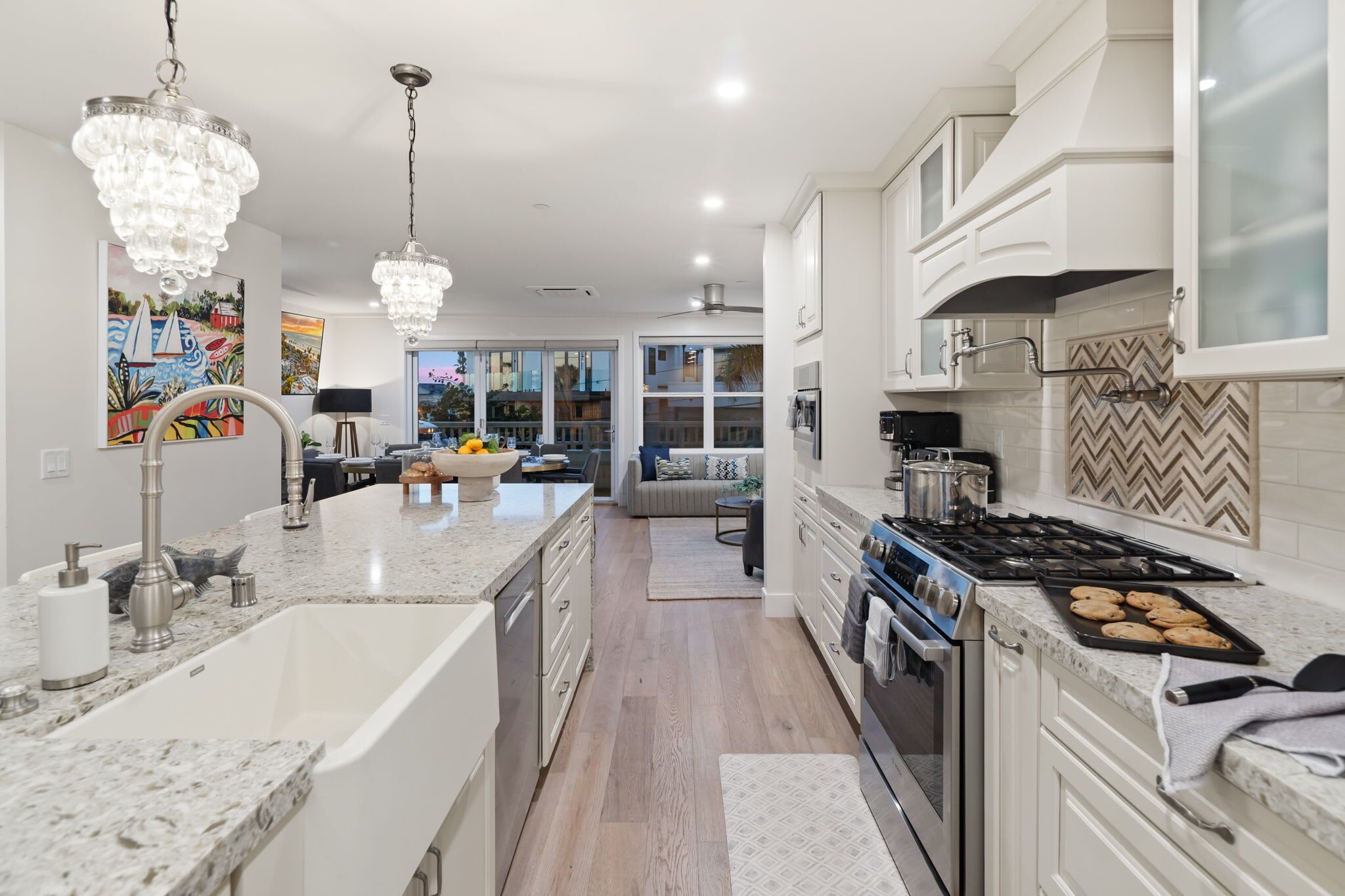 A modern kitchen with a central island, stainless steel appliances, and a herringbone tile backsplash.