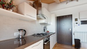 A modern kitchen with a gas stove, oven, and a coffee maker on the counter.