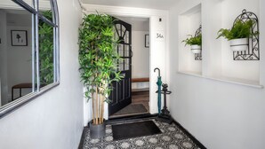 A hallway with a potted plant, a black door, a number sign, and a wall-mounted plant holder. - Stylish 16th century apartment in Petersfield town centre (Petersfield)