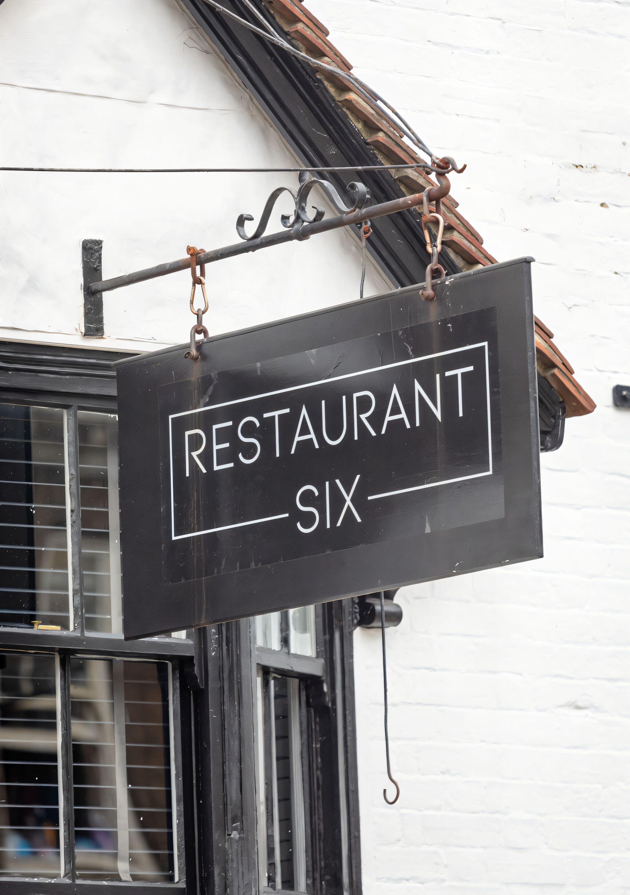 A restaurant sign with the name "RESTAURANT SIX" hanging from a building.