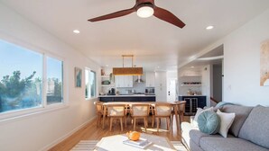 A modern kitchen with wooden cabinets, a dining area with a table and chairs, and a living room with a sofa and a coffee table.