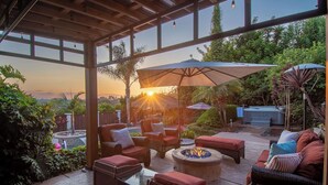 An outdoor patio with wicker furniture, a fire pit, and a view of the sunset.