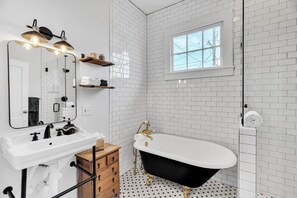 A bathroom with a white sink, black bathtub, and a window.
