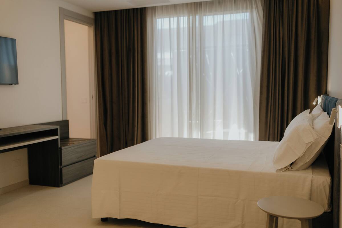 A hotel room with a bed, a desk, a chair, and a TV.