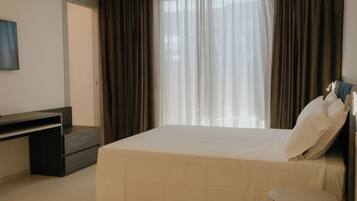 A hotel room with a bed, a desk, a chair, and a TV.