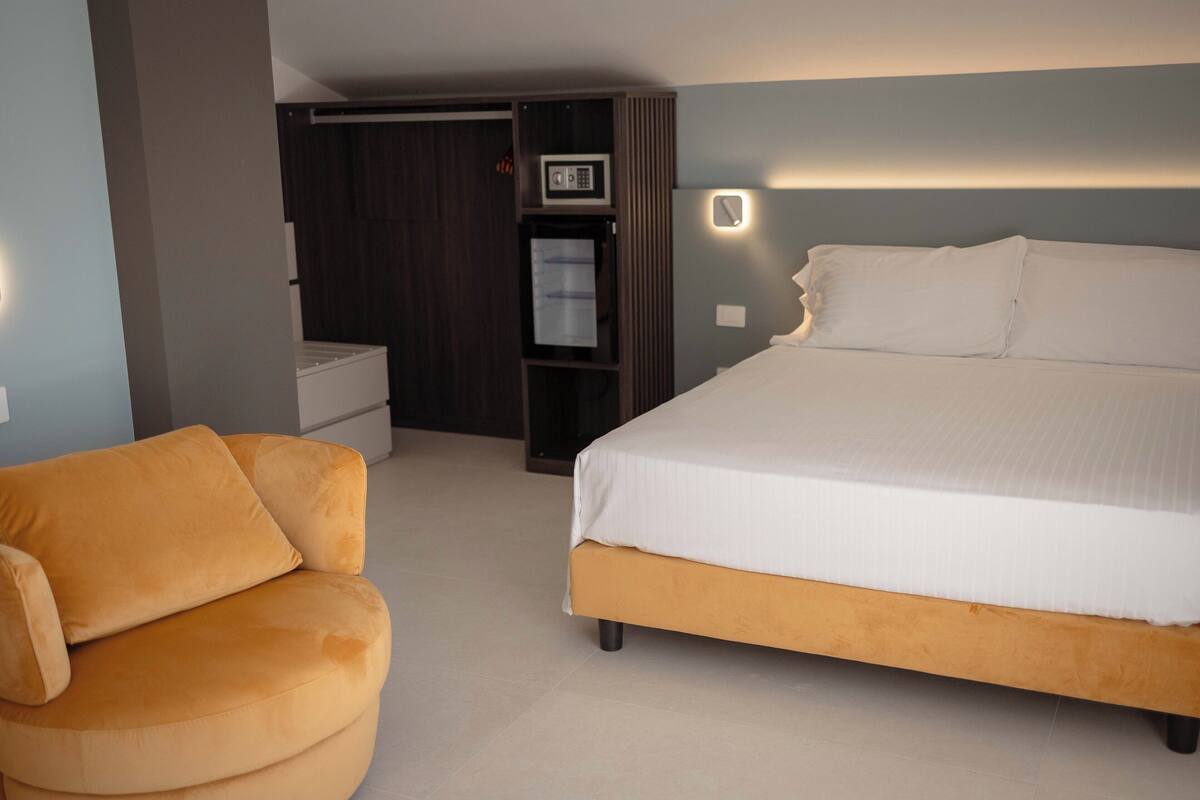 A bedroom with a bed, a sofa, a wardrobe, and a microwave.