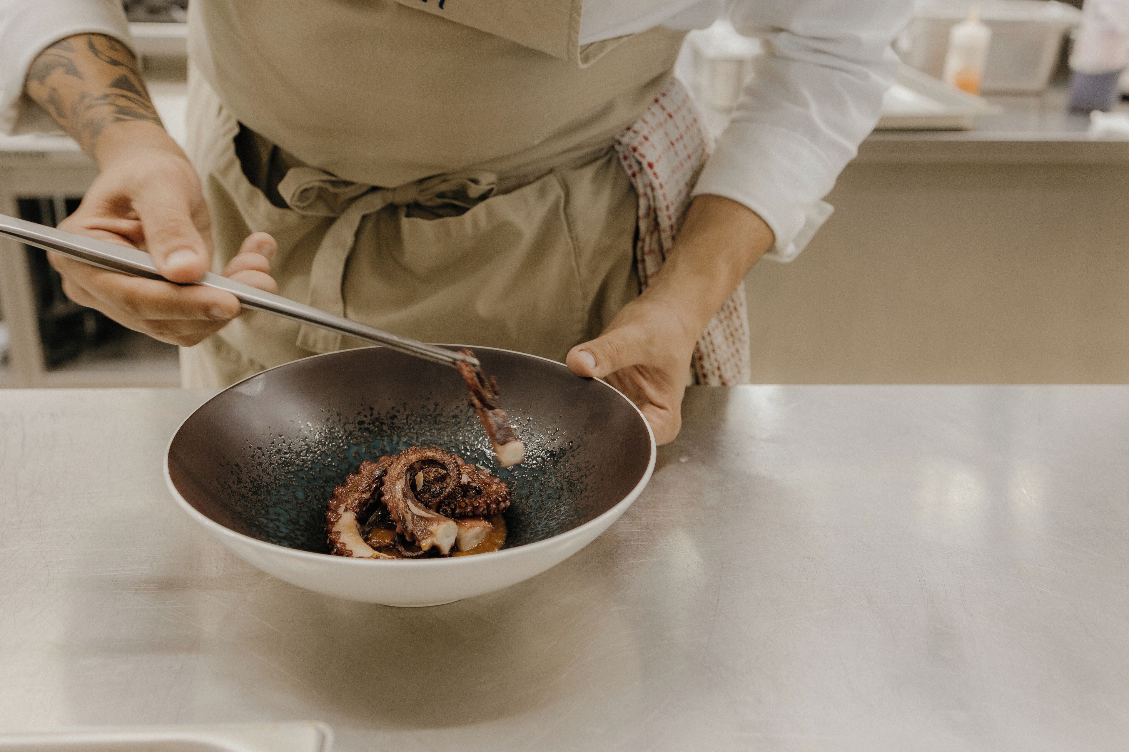 A person cooking in a kitchen with a bowl on the counter.