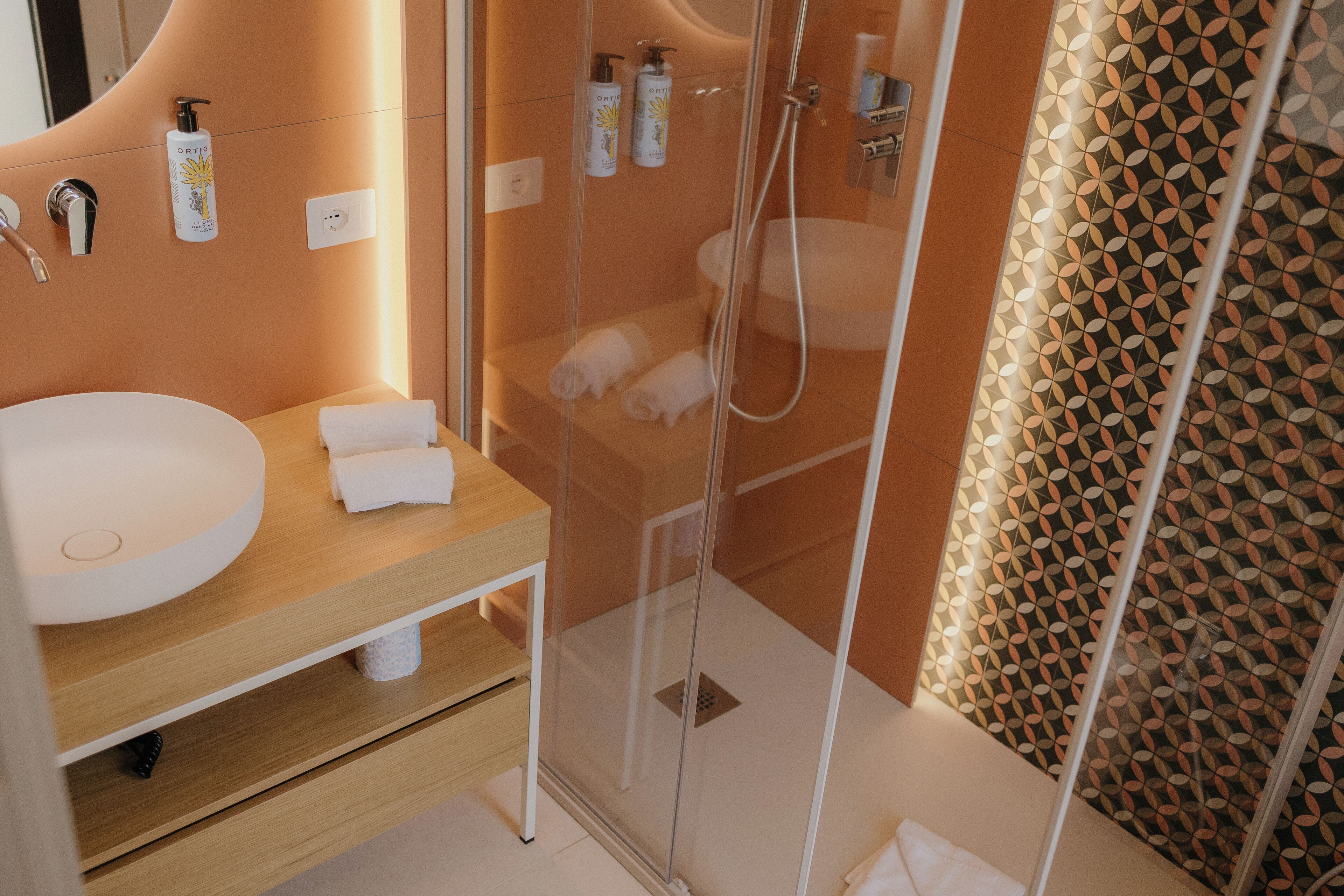 Un baño moderno con un lavamanos grande, una ducha con cerramiento de vidrio y un revestimiento de pared estampado.