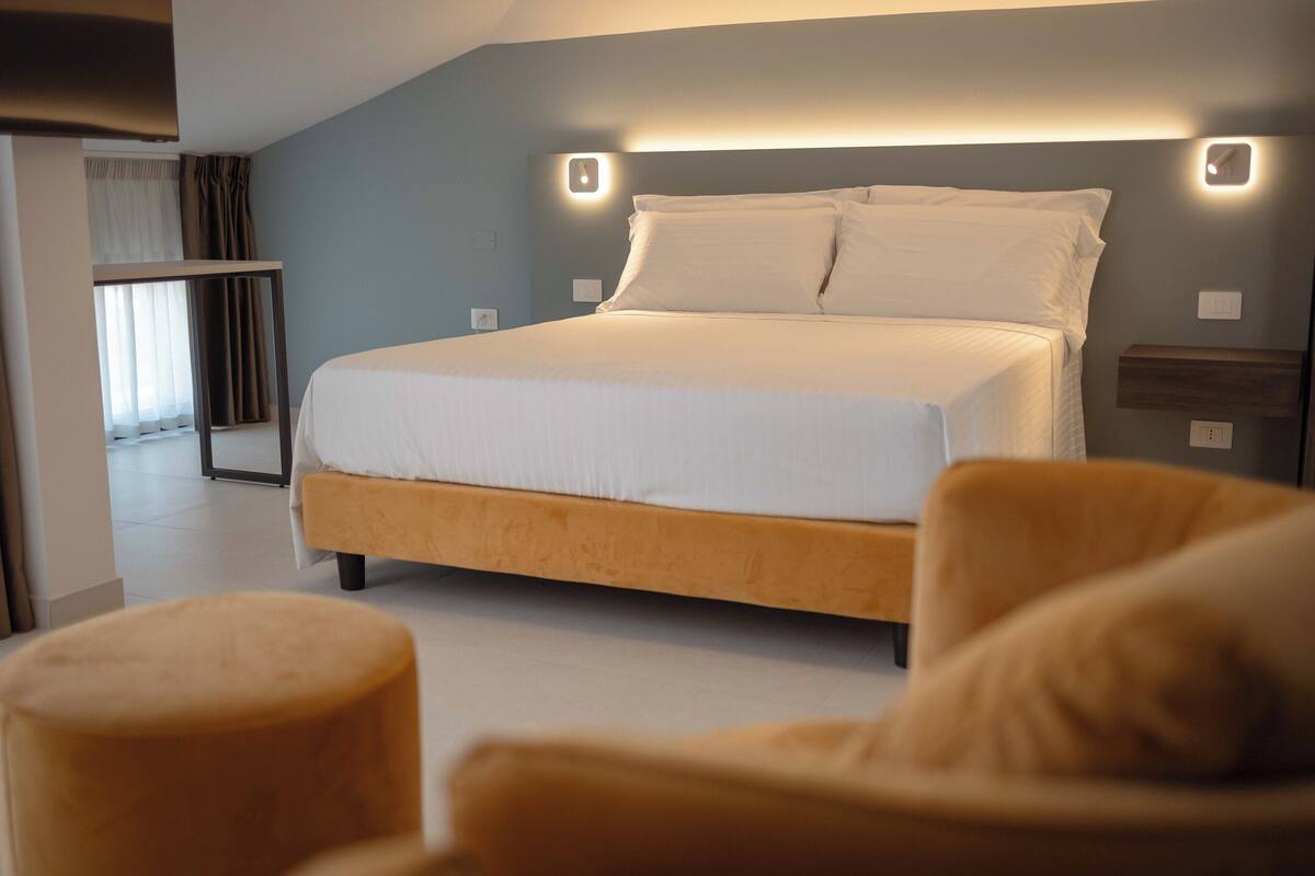 A modern bedroom with a large bed, a bedside table, and a nightstand.
