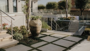 Un espace extérieur moderne agrémenté d’un grand bac à plantes, d’un escalier et d’une rambarde en verre.