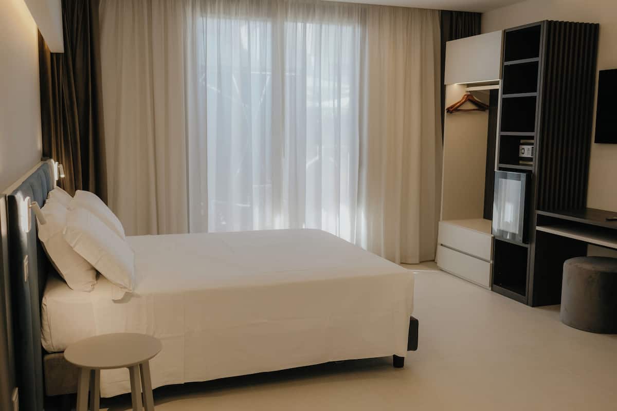 A hotel room with a bed, a small table, a wardrobe, and a TV.