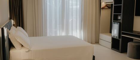 Una habitación de hotel con una cama, una mesita, un armario y un televisor.