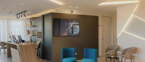 A modern hotel lobby with a reception desk, seating area, and a large abstract painting on the wall.