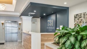 A reception area with a reception desk, a reception number sign, a reception area with a plant, and a door to the elevator.