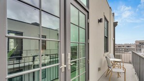 A balcony with a view of the city, a glass door, and a small table with chairs.