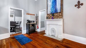 A spacious living room with hardwood flooring, a fireplace, and a dining area with a black cabinet and chairs.
