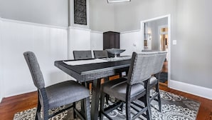 A dining area with a rectangular table, six chairs, a chandelier, and a decorative wall panel.