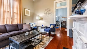 A living room with a brown leather sofa, a wooden coffee table, a blue armchair, and a white fireplace.
