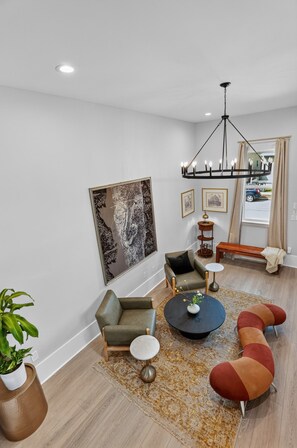A modern living room with a sofa, armchair, coffee table, and a large abstract painting.