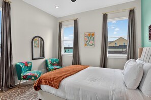 A hotel room with a bed, two chairs, a mirror, and artwork on the walls.