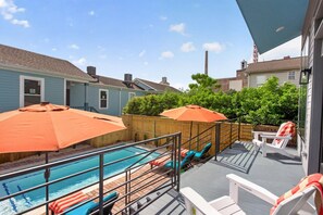 Un jardin avec une piscine, des chaises longues et des parasols.
