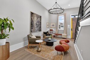 A modern living room with a sofa, armchairs, a coffee table, and a chandelier.