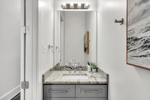 A bathroom with a marble sink, two towel racks, a large mirror, and a framed picture on the wall. - Apt on Magazine St. - Walk to Shops & Restaurants (New Orleans)
