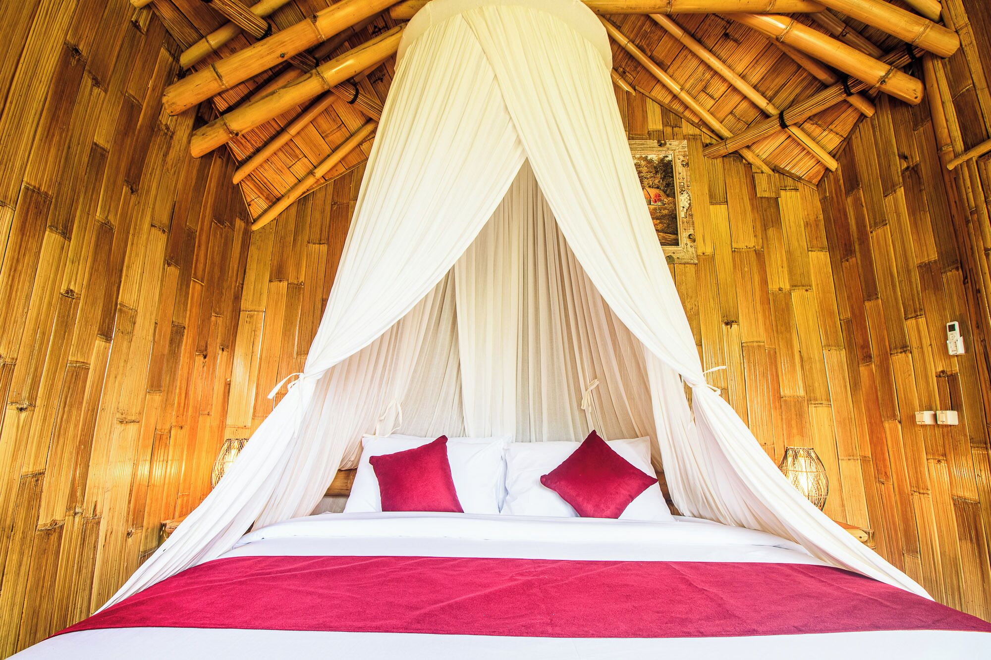 Uma cama com dossel em um quarto com paredes de bambu.
