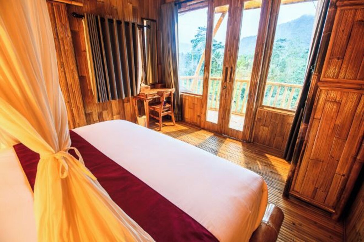Una habitación de madera con una cama, un escritorio y vistas al exterior.
