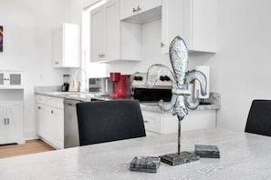Una cocina moderna con armarios blancos, encimera de mármol y una decoración de metal con motivos de fleur-de-lis.