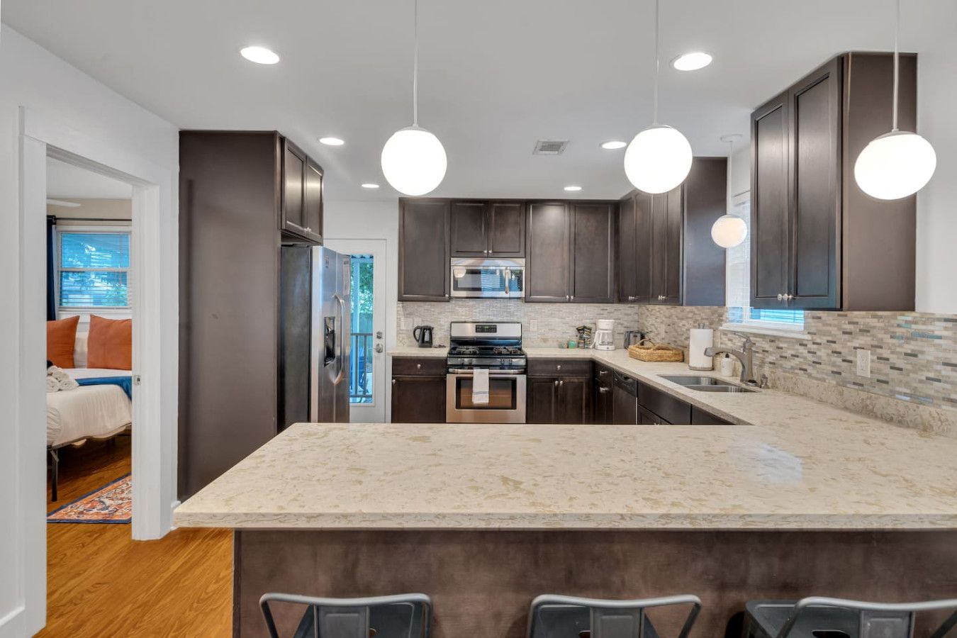 A modern kitchen with dark wood cabinets, a large island, and pendant lighting.