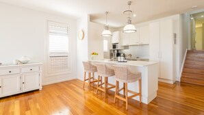 A modern kitchen with a central island, bar stools, and pendant lighting.
